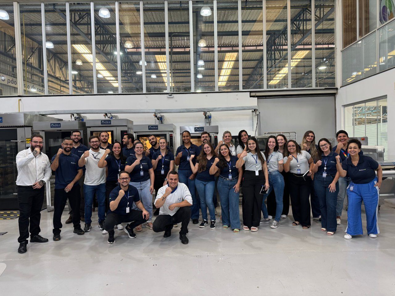 Um grupo de pessoas está posando para uma foto em um armazém.