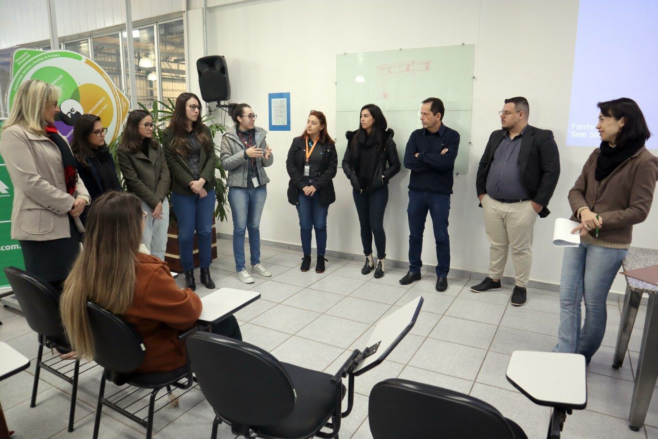 Um grupo de pessoas está em pé formando um círculo em uma sala.
