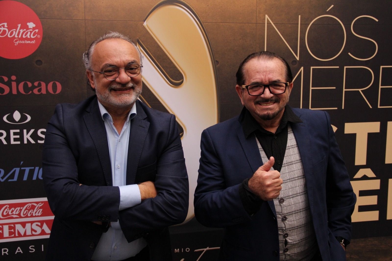 Dois homens parados em frente a uma placa que diz nos mere