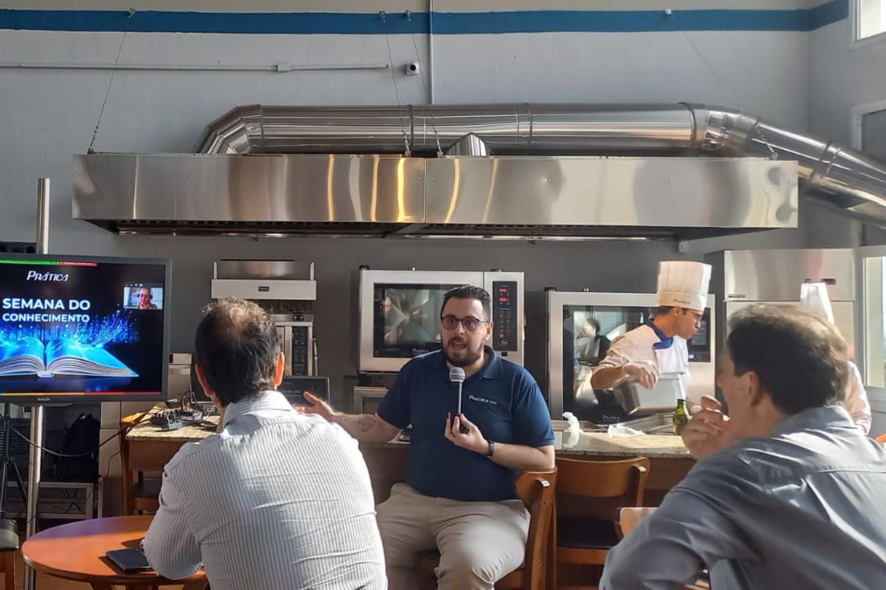 Um grupo de homens estão sentados à mesa em uma cozinha conversando entre si