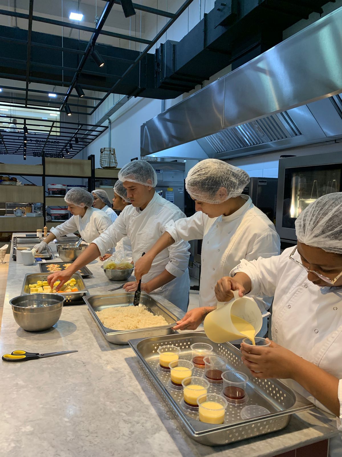Um grupo de chefs está preparando comida em uma cozinha.