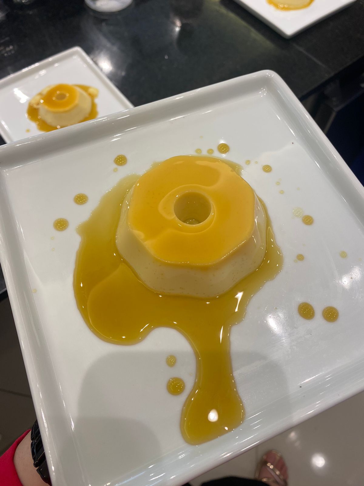 Uma pessoa está segurando um prato branco com uma sobremesa