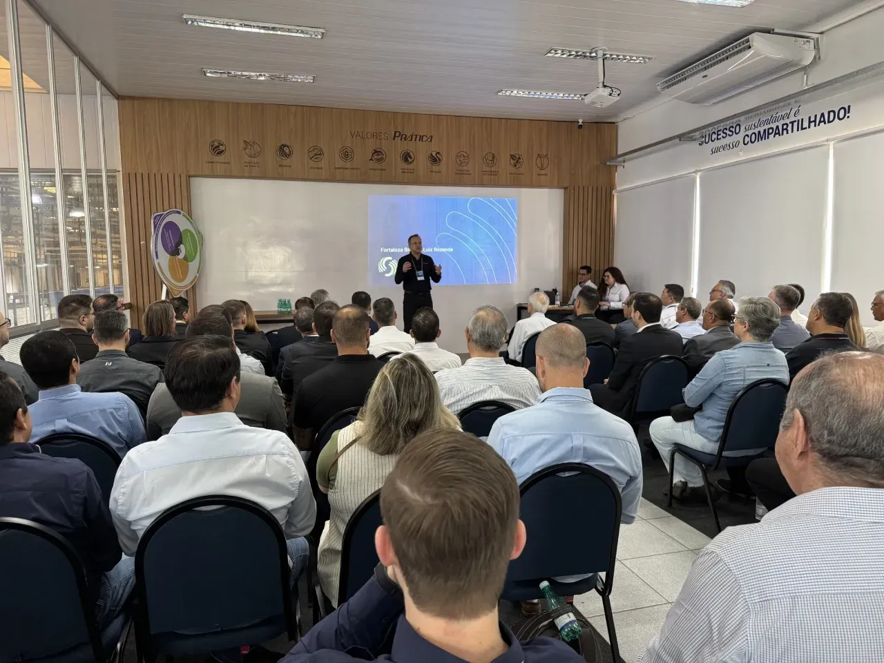 Um homem fazendo uma apresentação para uma plateia sentada em uma sala de conferências.