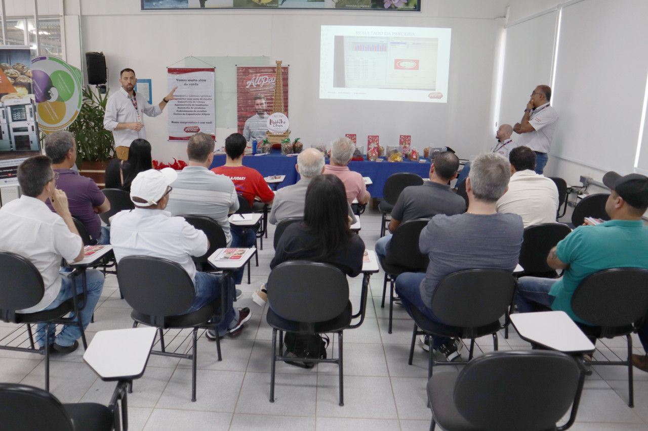Um grupo de pessoas está sentado em uma sala de aula assistindo a uma apresentação.