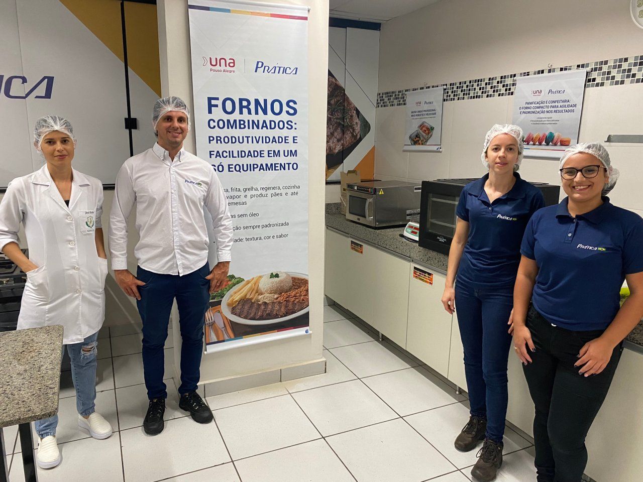 Um grupo de pessoas em pé, uma ao lado da outra, em uma cozinha.