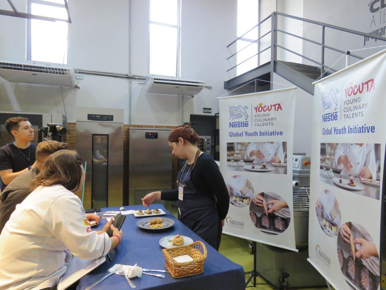 Um grupo de pessoas está sentado ao redor de uma mesa na cozinha.