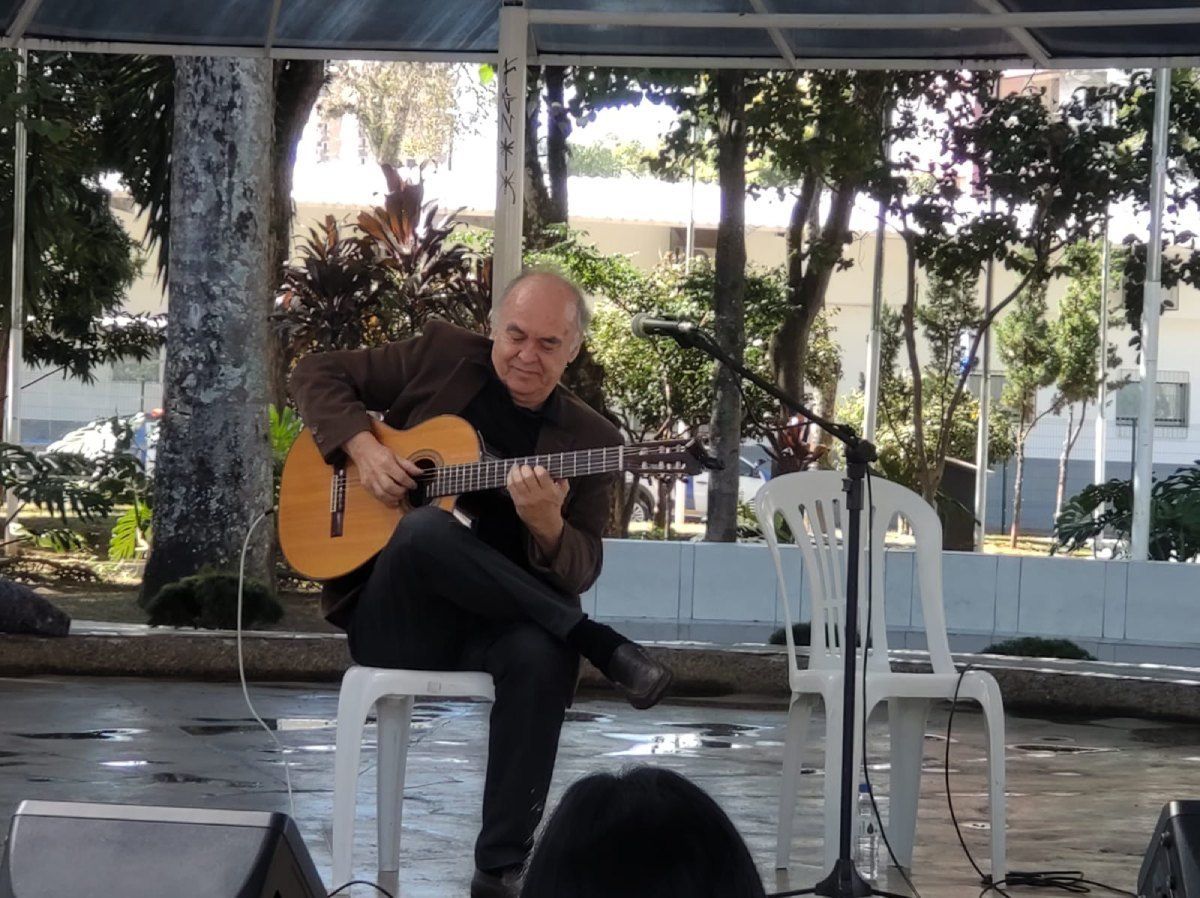 Um homem está tocando violão na frente de uma multidão
