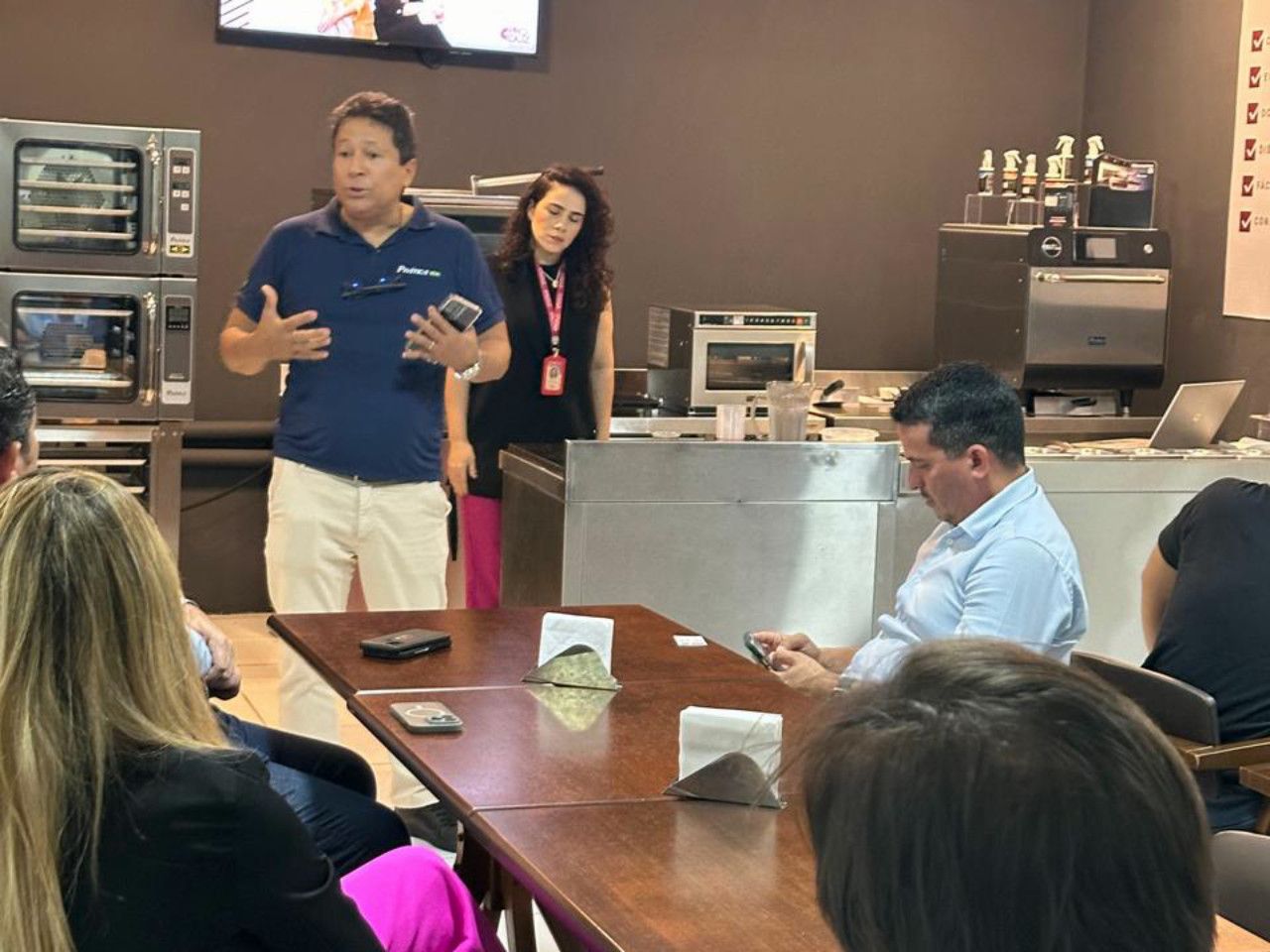 Um homem está fazendo uma apresentação para um grupo de pessoas em uma mesa.