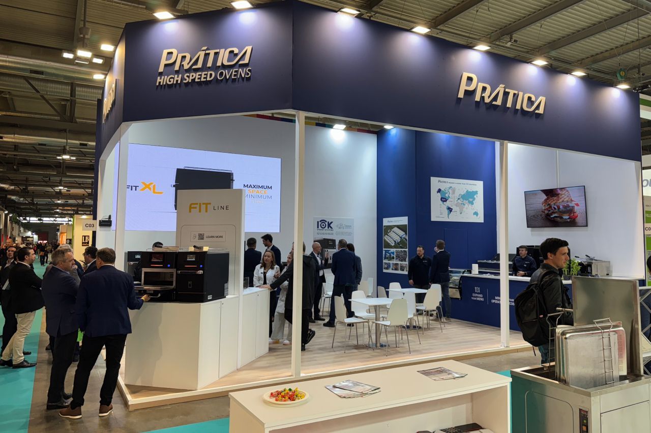 Um estande da Pratica, com design azul e branco, com pessoas circulando.