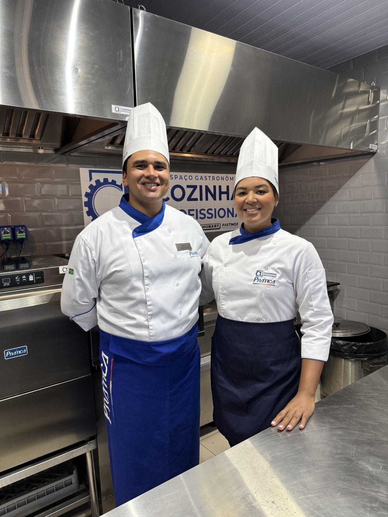 Um homem e uma mulher estão posando para uma foto em uma cozinha.