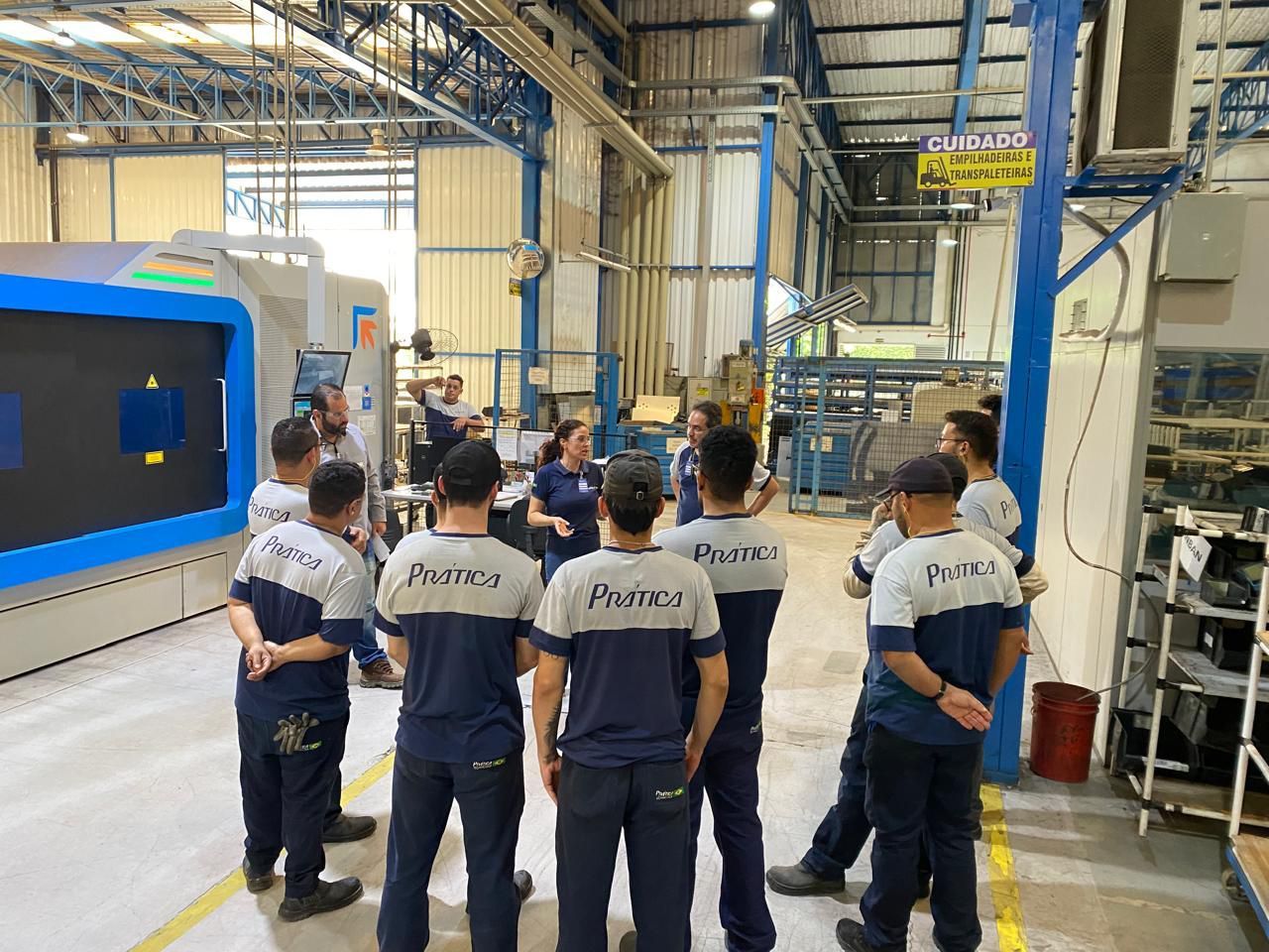 Um grupo de pessoas está em uma fábrica conversando entre si.