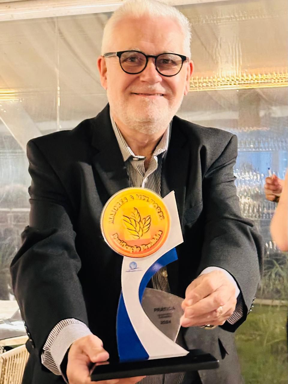 Um homem de terno e gravata está segurando um troféu