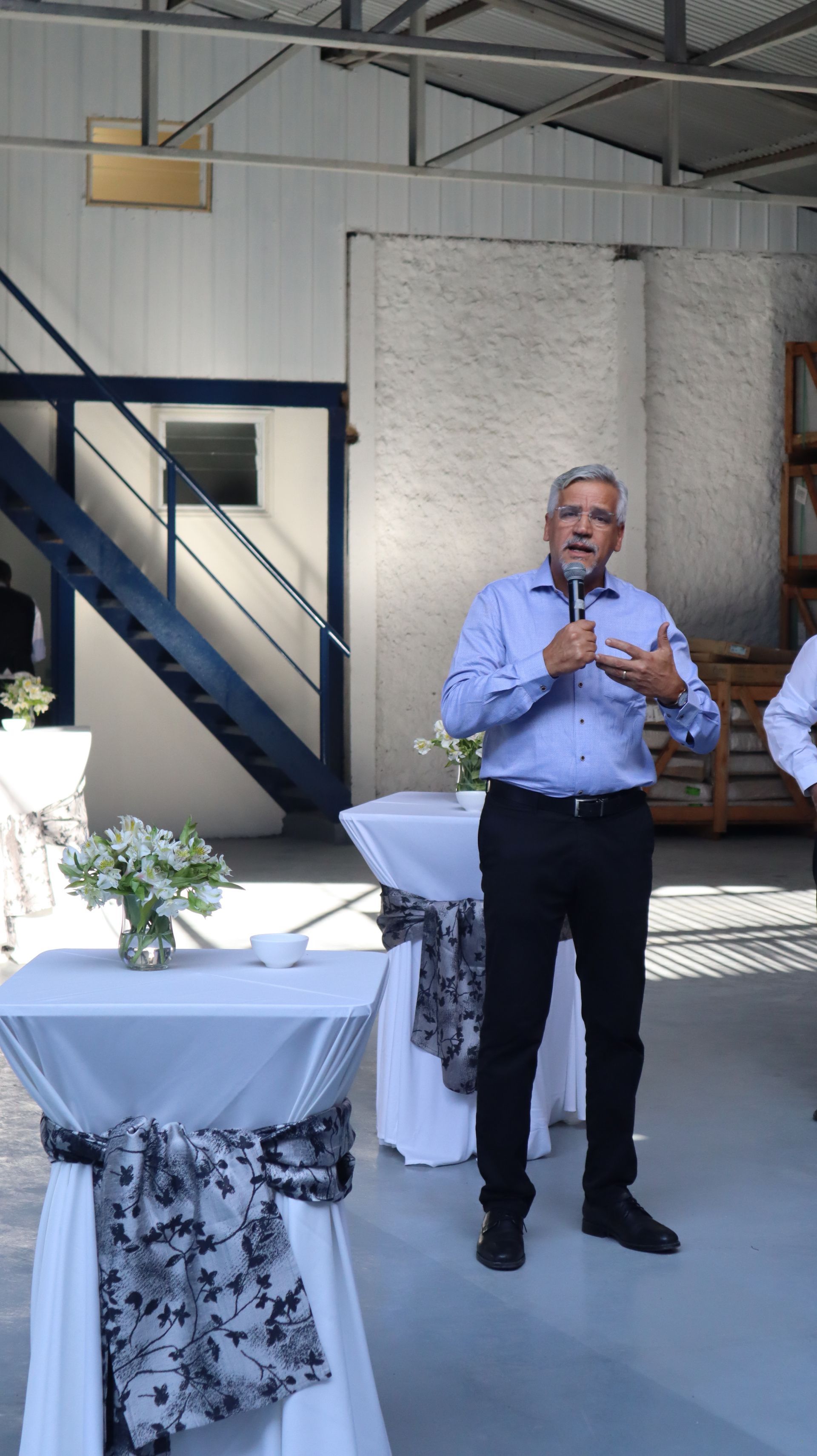 Um homem está em pé em uma sala falando em um microfone