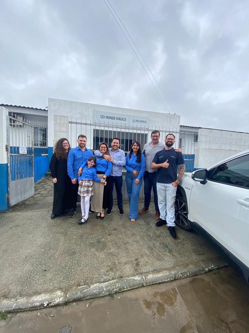 Um grupo de pessoas está posando para uma foto em frente a um prédio.