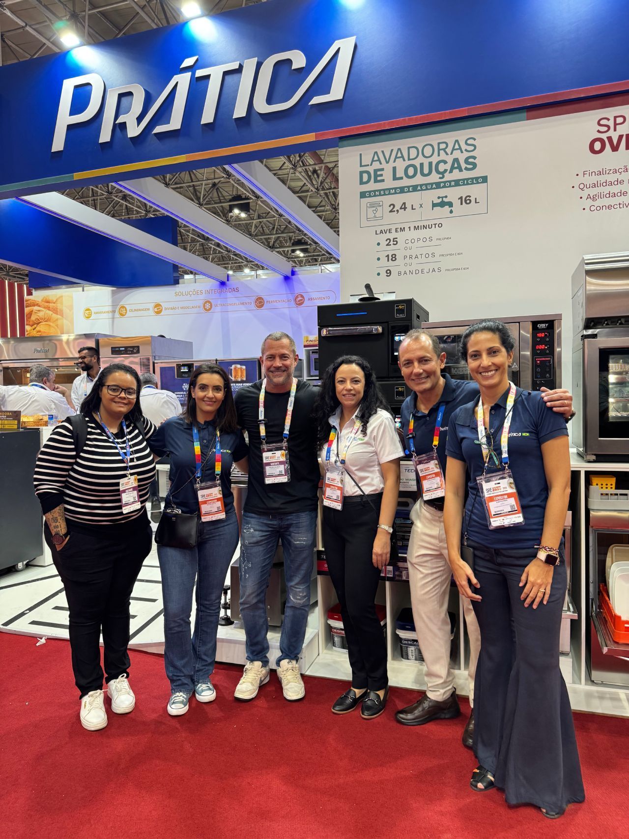 Um grupo de pessoas está posando para uma foto em frente a um estande em uma convenção.