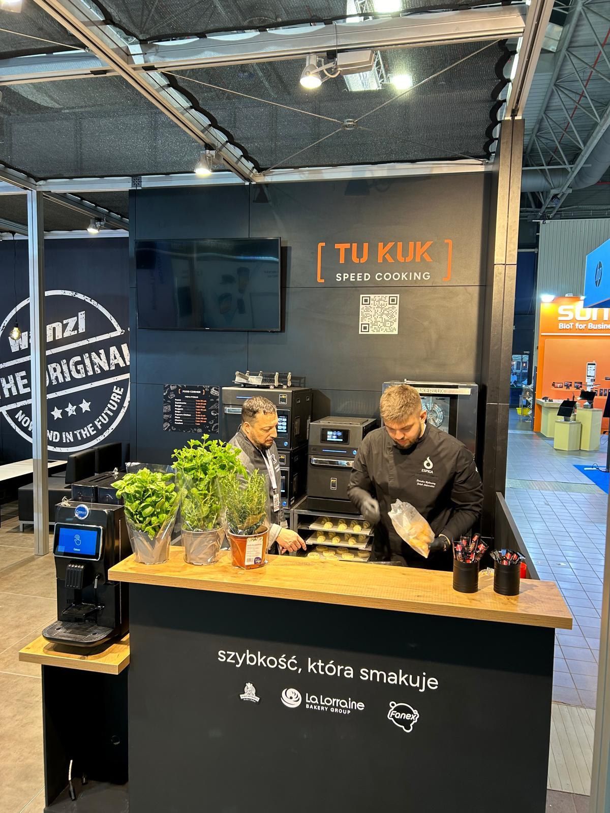 Dois homens estão de pé atrás de um balcão em uma cafeteria.