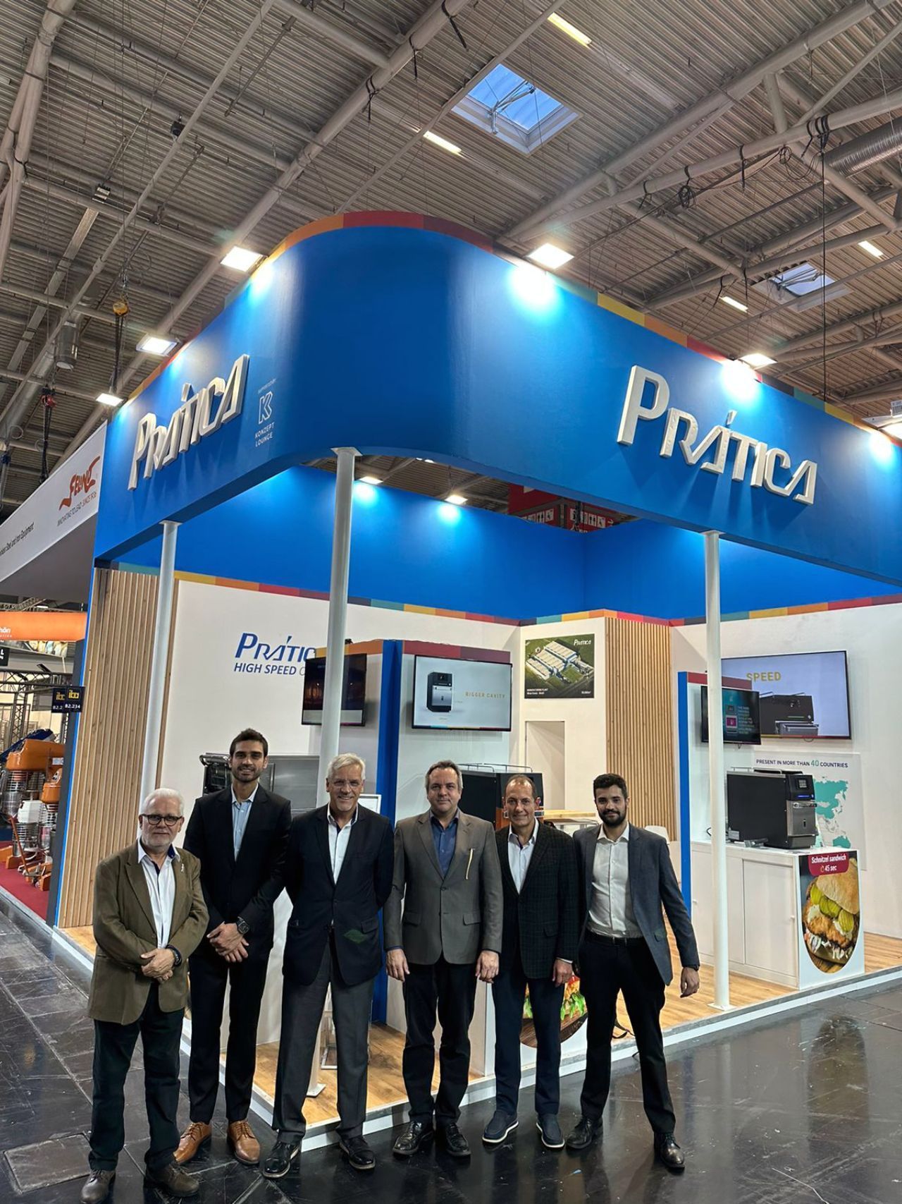 Um grupo de homens está em frente a um estande em uma convenção.