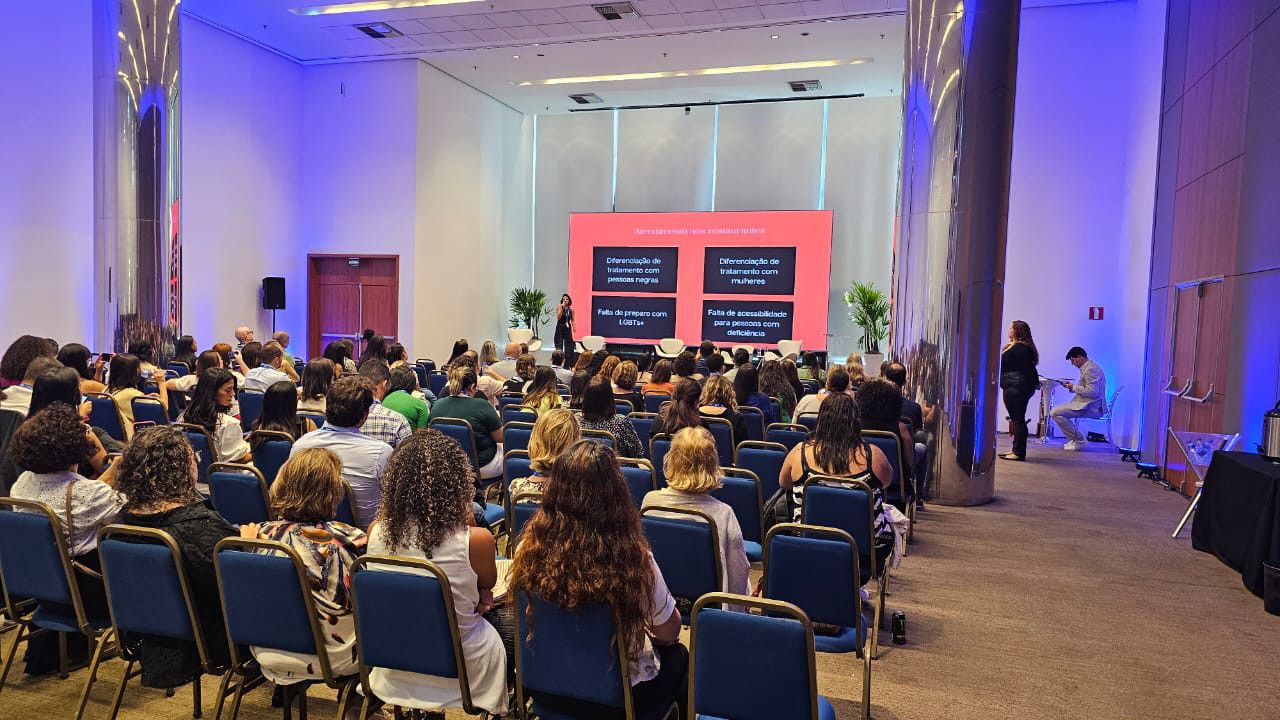 Um grande grupo de pessoas está sentado em uma sala de conferências.