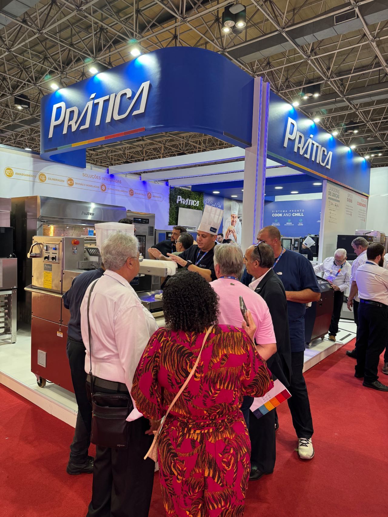 Um grupo de pessoas está em volta de um estande em uma convenção.