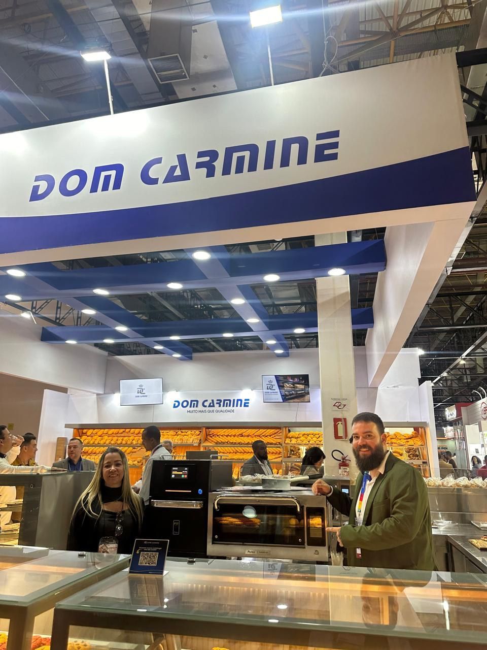 Um homem está parado em frente a uma placa que diz dom carmine