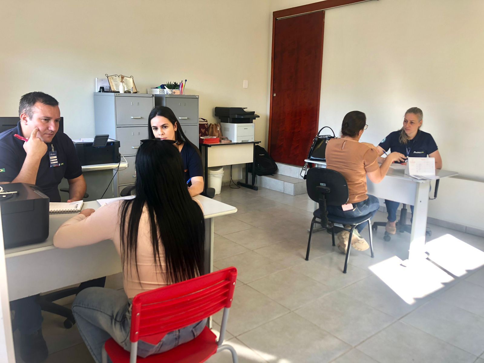 Um grupo de pessoas está sentado em mesas em uma sala.