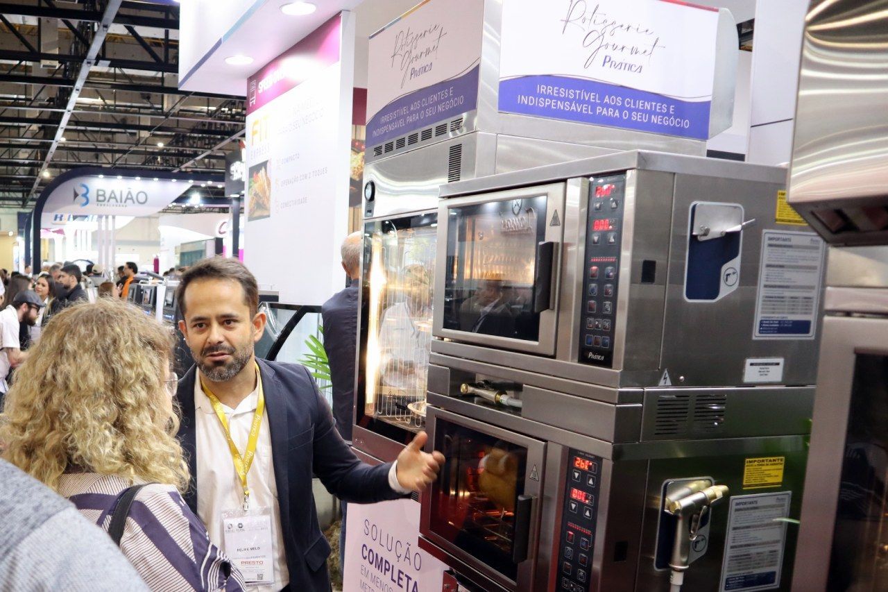 Um homem está parado em frente a uma pilha de fornos conversando com uma mulher.