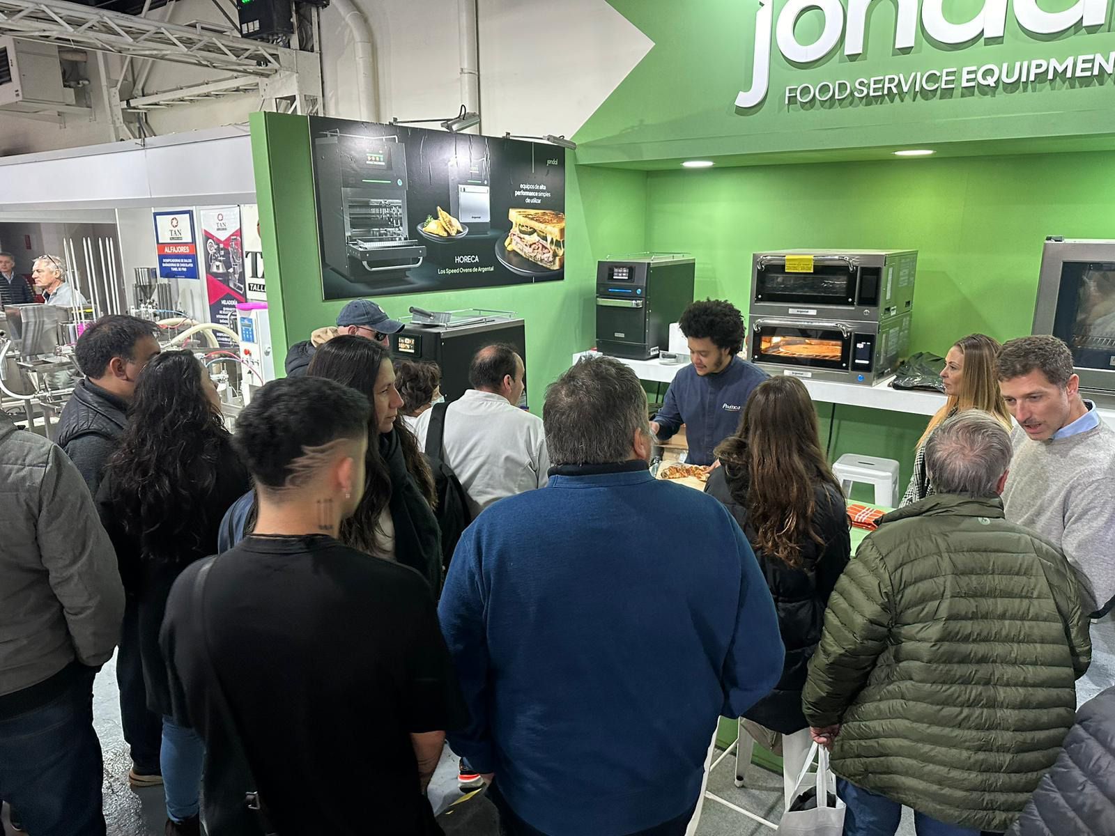 Um grupo de pessoas está em pé em frente a uma parede verde.