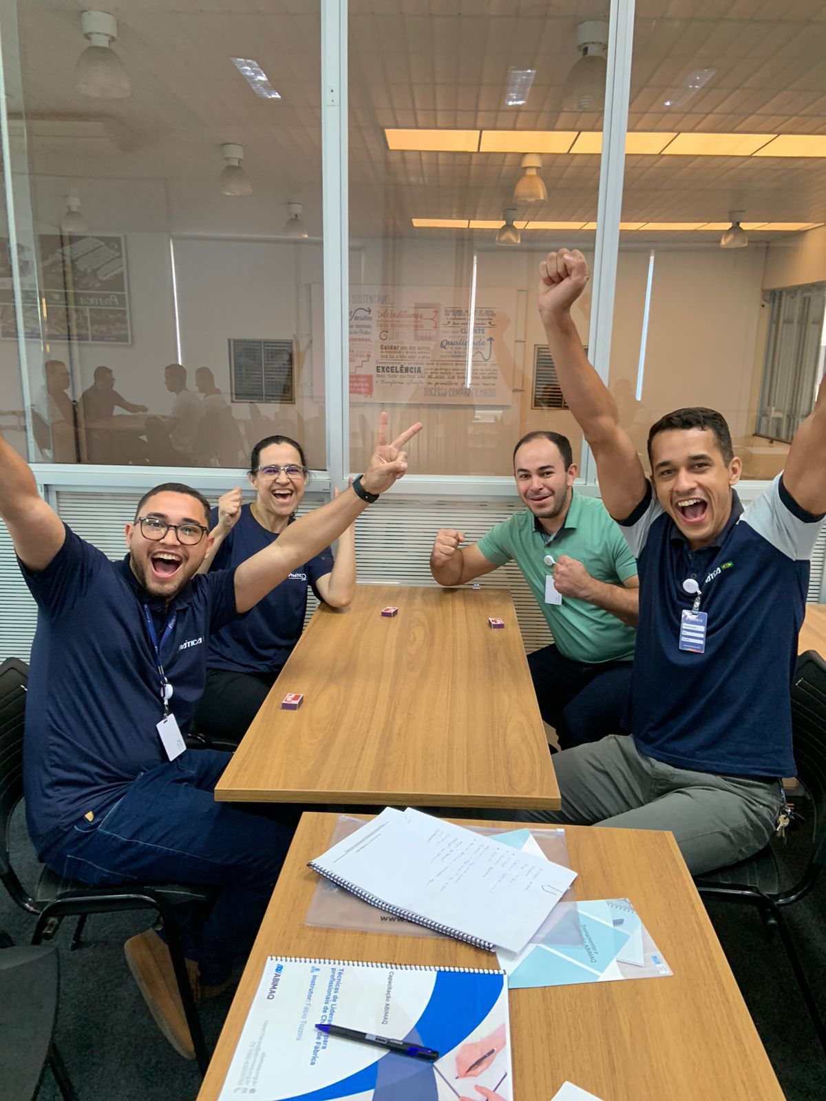 Um grupo de homens está sentado à mesa com os braços no ar.