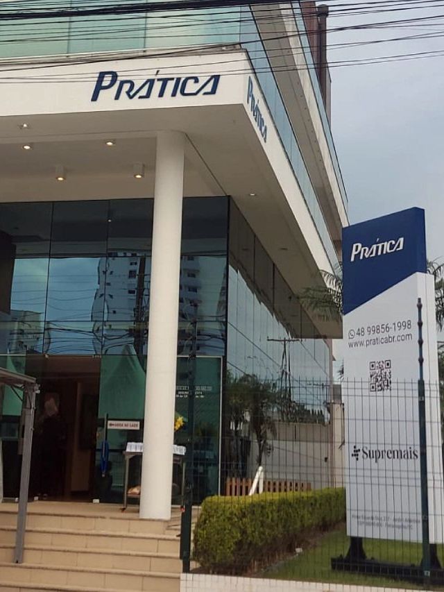 Um grupo de pessoas está do lado de fora de um prédio com uma tenda na frente.