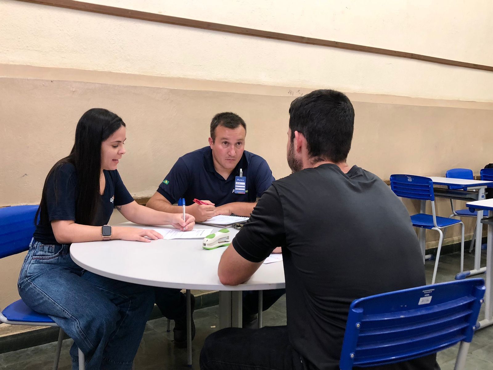 Um grupo de pessoas está sentado ao redor de uma mesa conversando entre si.