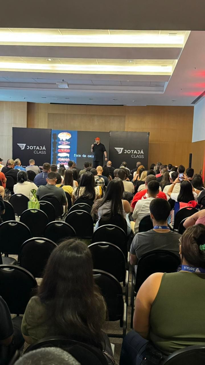 Um homem está fazendo uma apresentação para um grande grupo de pessoas em uma sala de conferências.