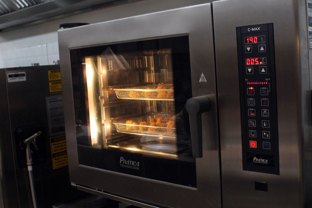 Um forno de aço inoxidável está sendo usado para cozinhar alimentos