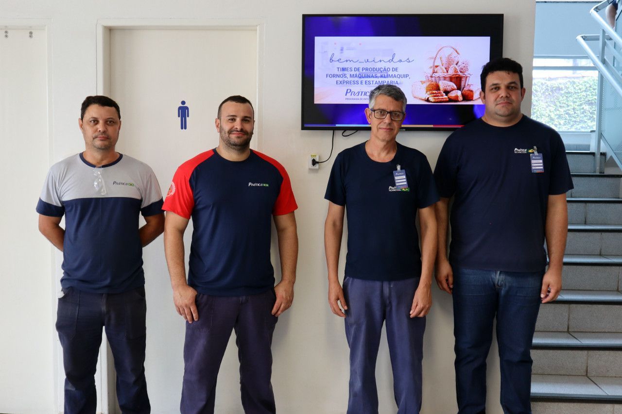 Um grupo de homens em pé na frente de uma televisão