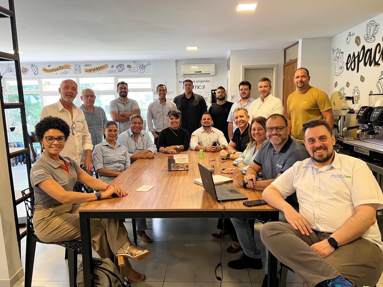 Um grupo de pessoas está sentado ao redor de uma mesa com laptops.