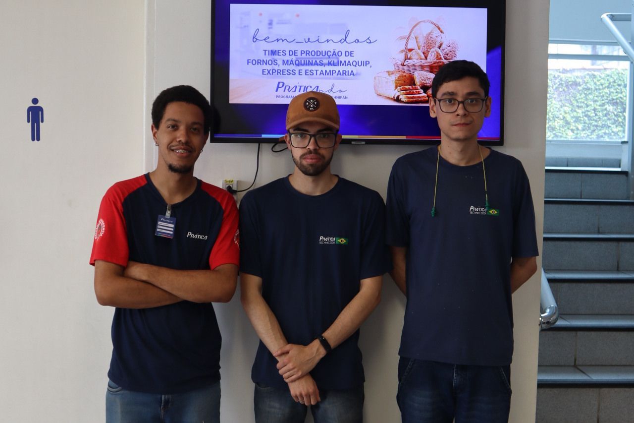 Três homens em pé na frente de uma placa que diz bienvenidos