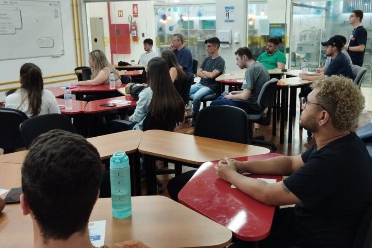 Um grupo de pessoas está sentado em carteiras em uma sala de aula