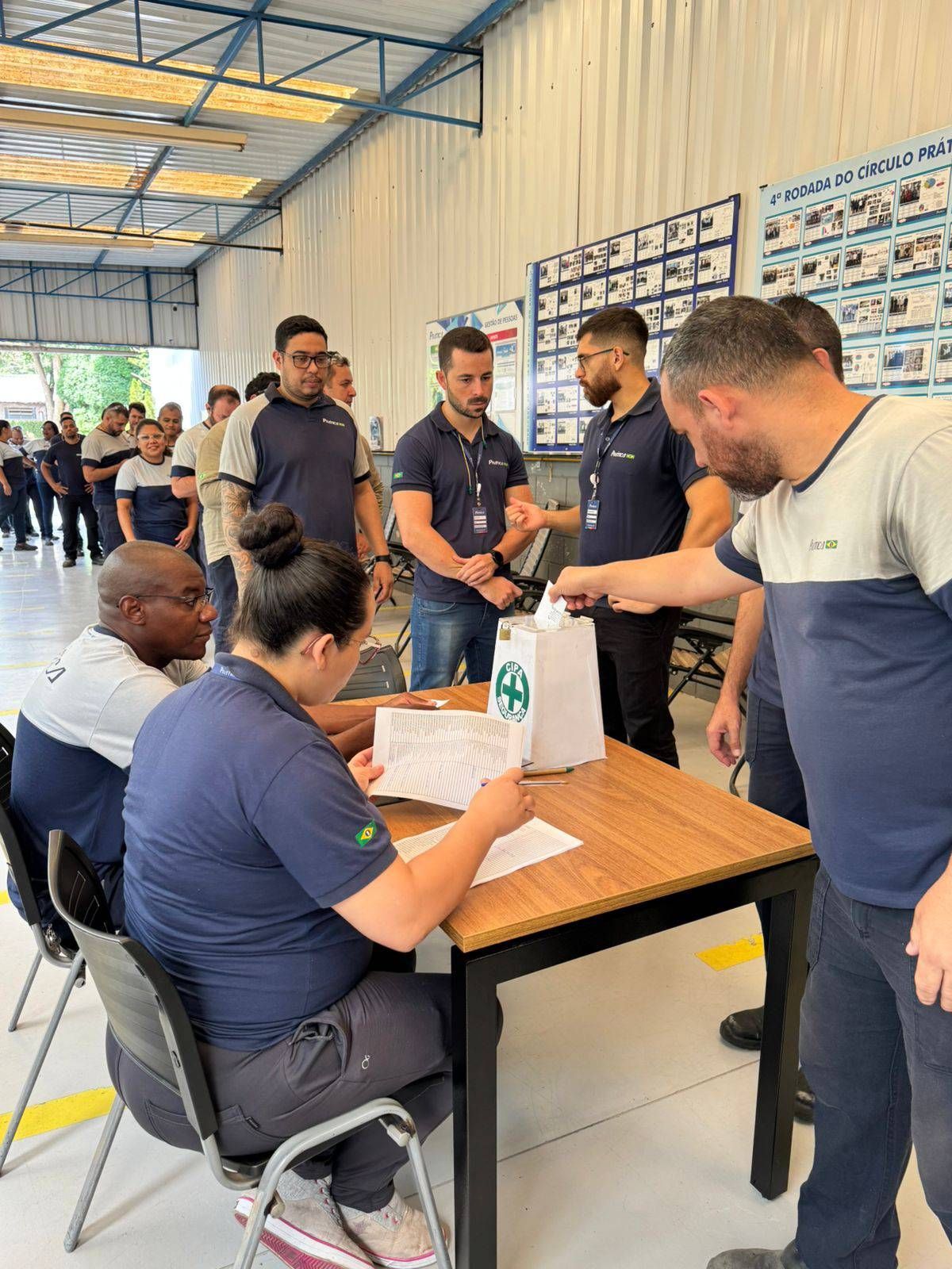 Um grupo de pessoas está em pé ao redor de uma mesa em uma sala.