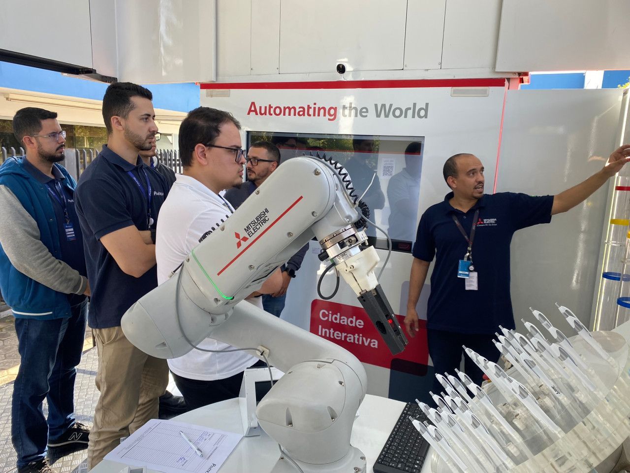 Um grupo de homens está em volta de um braço robótico.