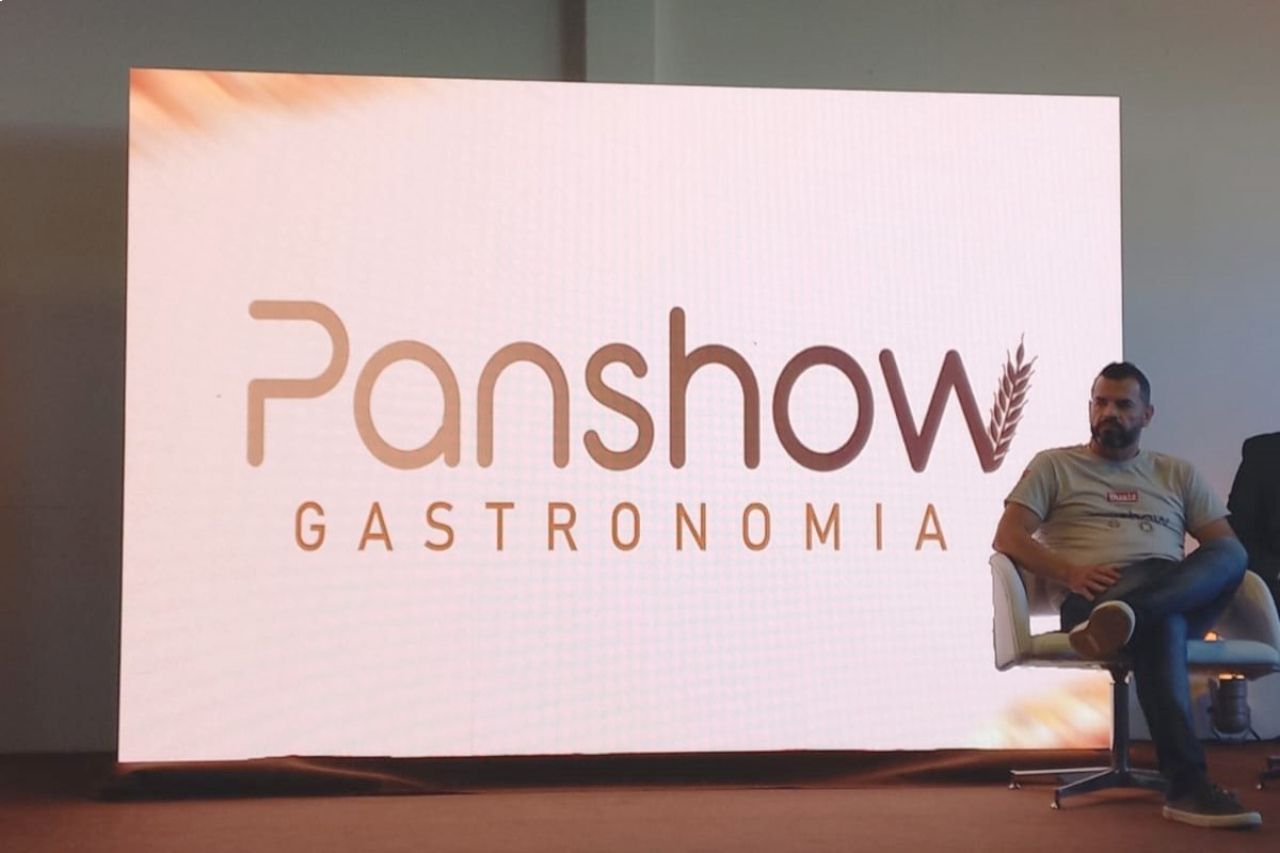 Um homem está sentado em frente ao logotipo da Panshow.