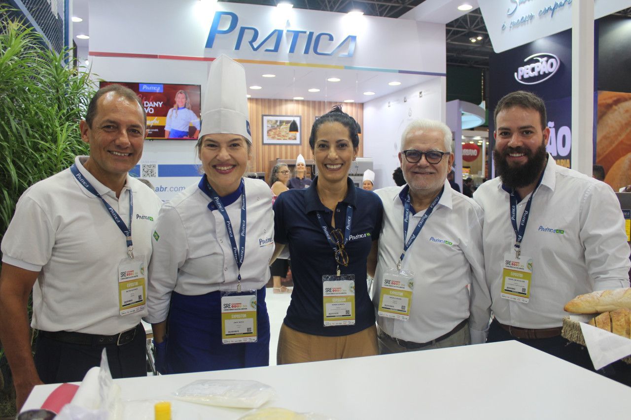 Um grupo de pessoas posa para uma foto em frente a uma placa que diz pratica.