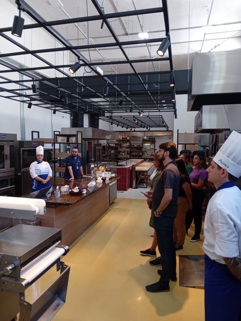 Um grupo de pessoas está em uma cozinha usando chapéus de chef