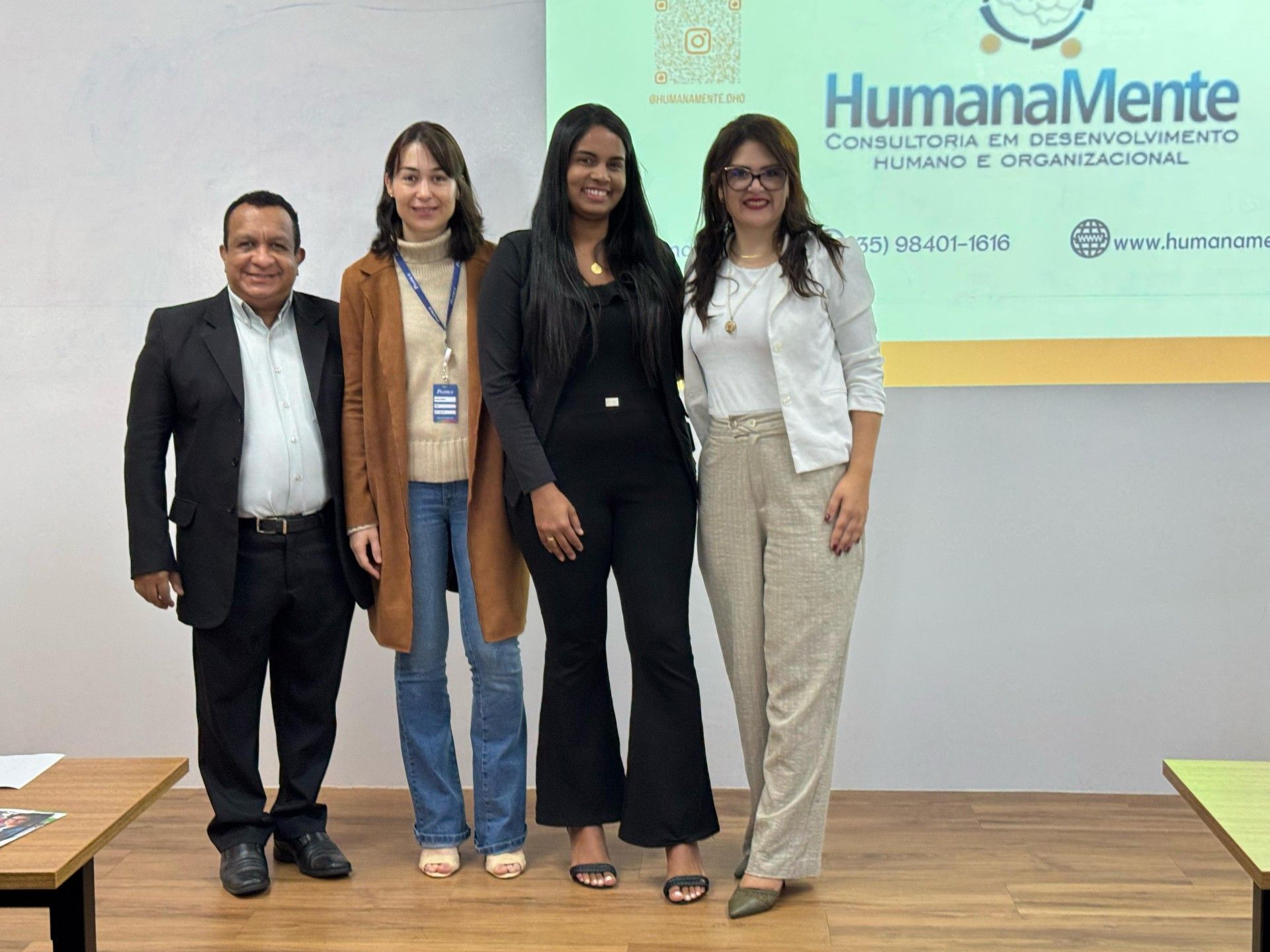 Um grupo de pessoas está posando para uma foto em frente a uma tela.