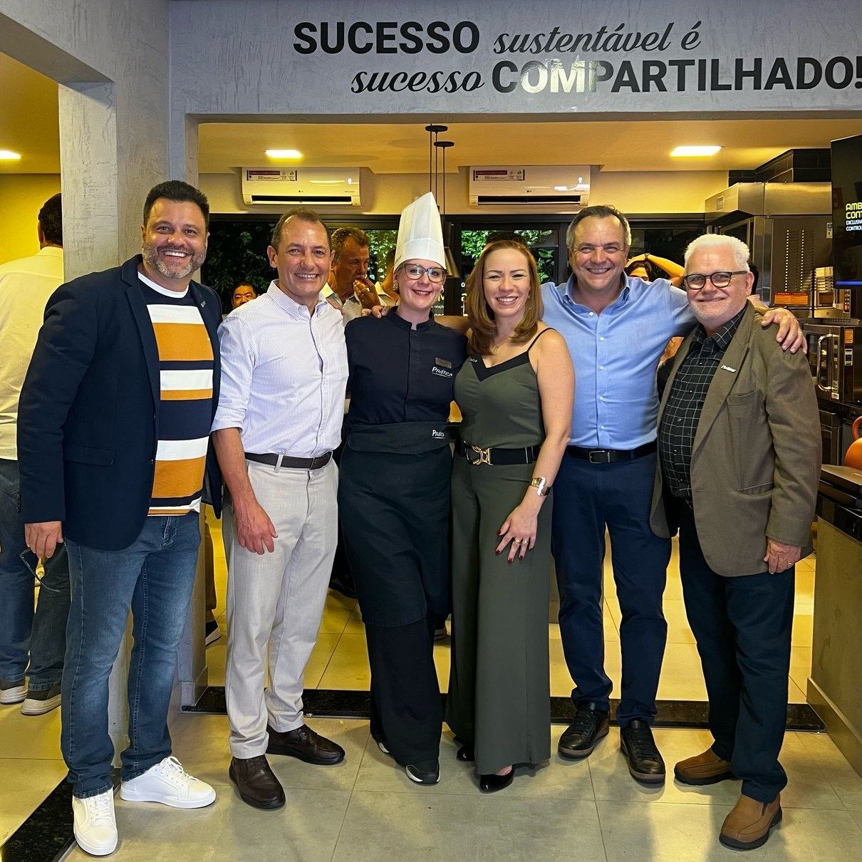 Um grupo de pessoas posando para uma foto em frente a uma placa que diz sucesso