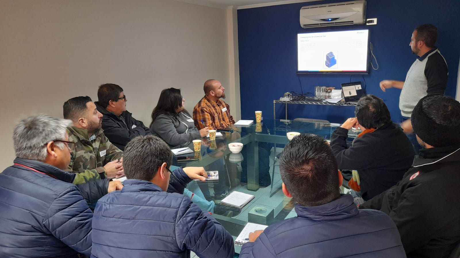 Um grupo de pessoas está sentado ao redor de uma mesa em uma sala de conferências.
