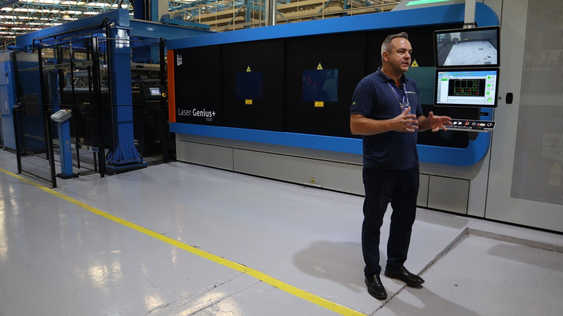 Um homem está parado em frente a uma máquina em uma fábrica.