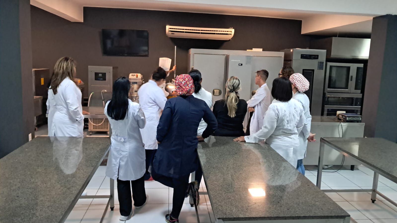 Um grupo de pessoas em pé ao redor de uma mesa em uma cozinha