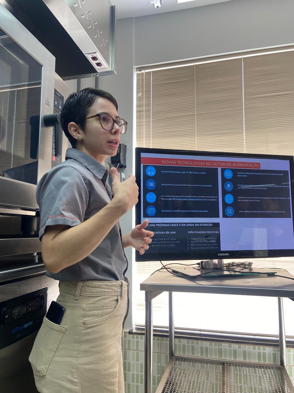 Uma mulher está fazendo uma apresentação em frente a uma tela de computador.