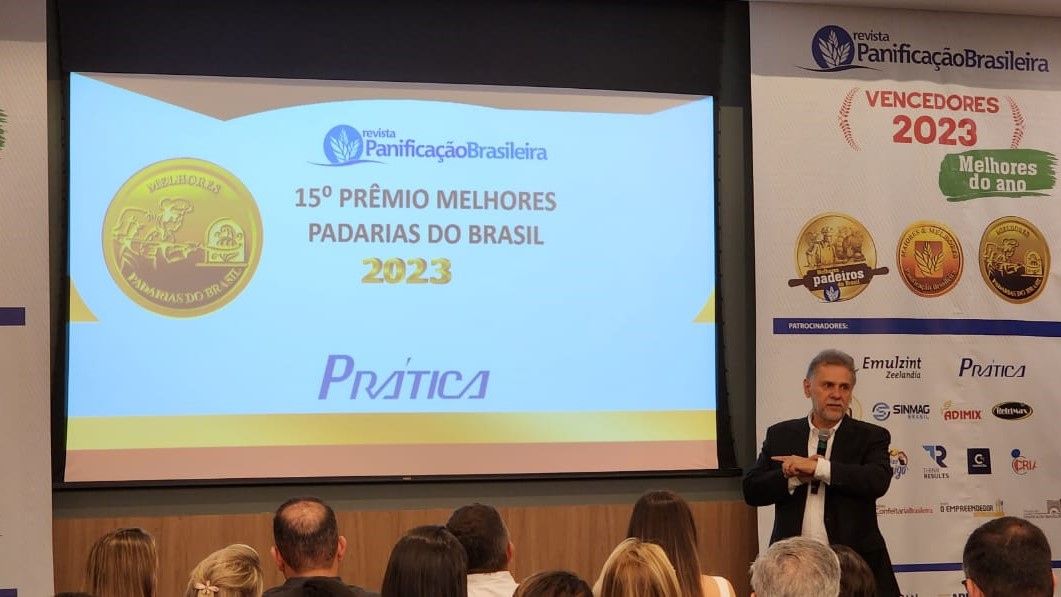 Um homem está fazendo uma apresentação para um grupo de pessoas em frente a uma tela grande.