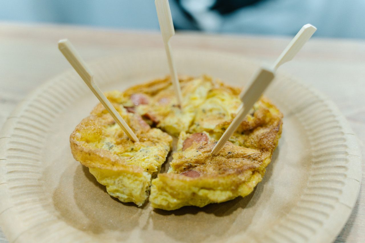 Um close de uma omelete em um prato de papel com garfos de madeira.