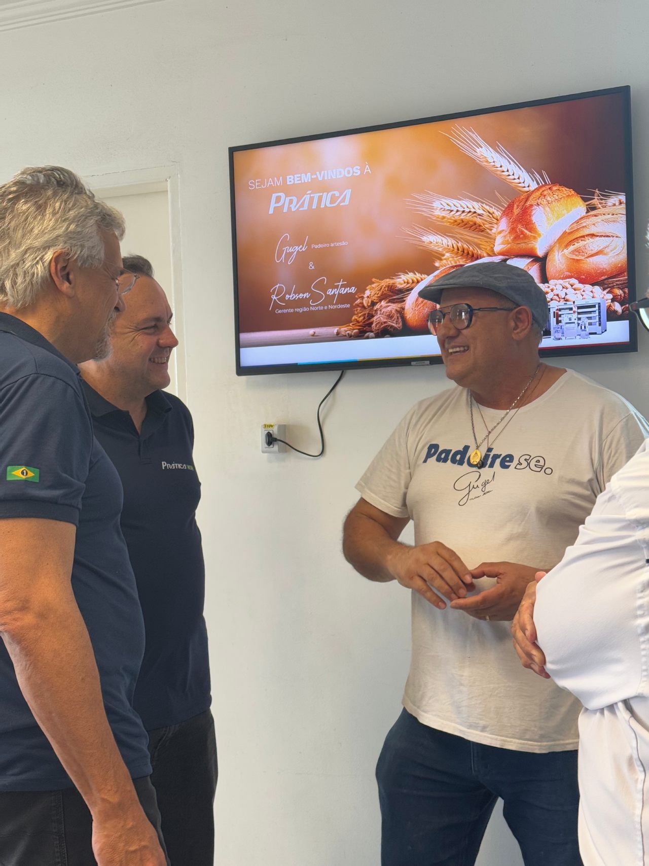 Um grupo de homens está em frente a uma TV de tela plana.